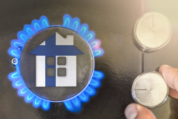 芬兰供暖季节或燃气使用情况。概念，一个房子的模型站在一个燃气锅炉的火焰附近在黑色的背景。在芬兰使用天然气的成本。图片下载