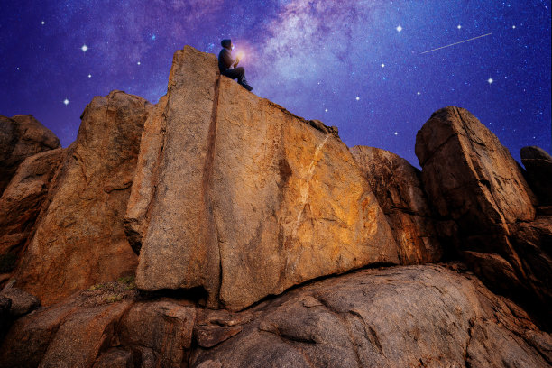 人们坐在户外古老的岩石上，在星空下冥想或祈祷图片下载