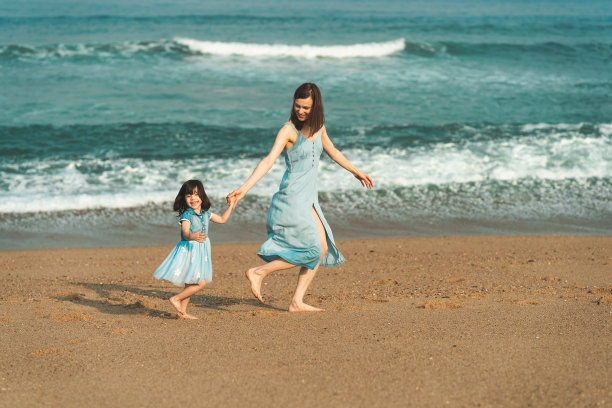 母亲和女儿在海边奔跑嬉戏的温馨照片图片下载