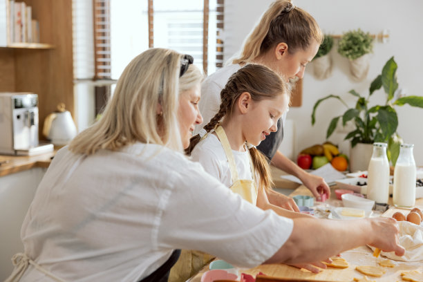 幸福的家庭在现代厨房准备面团，制作不同形状的饼干。为晚餐准备圣诞惊喜。年迈的奶奶，年轻的妈妈和女儿参与过程图片下载