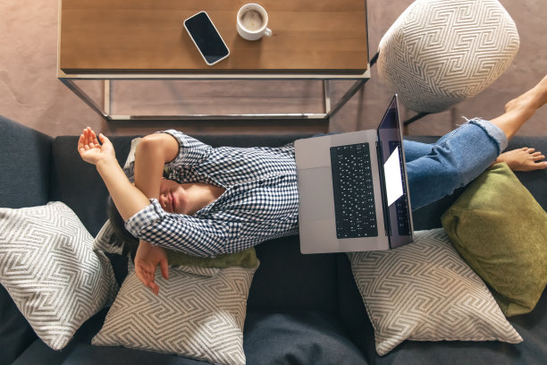 劳累工作的年轻女子坐在笔记本电脑前。图片下载