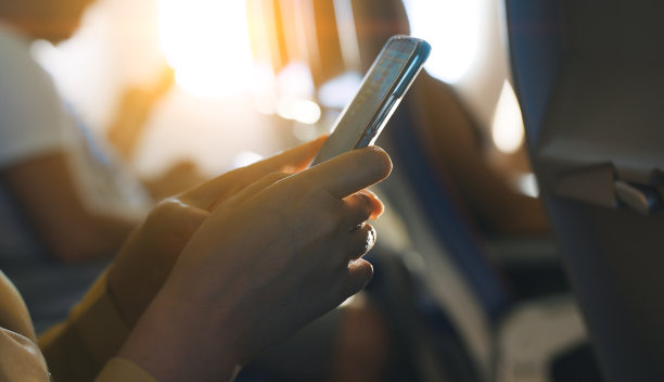 一名女子在飞机上使用智能手机。图片下载