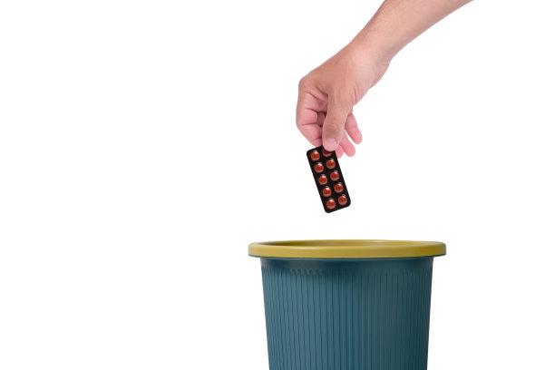 把包装好的药片扔进垃圾桶。孤立的白色背景。图片下载