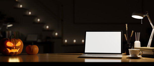 在黑暗的房间的办公桌工作空间在晚上与笔记本电脑模型和万圣节南瓜图片下载