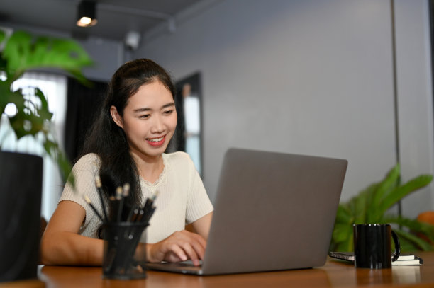 漂亮的亚洲女性办公室职员或大学生在咖啡店，使用她的笔记本电脑。图片下载