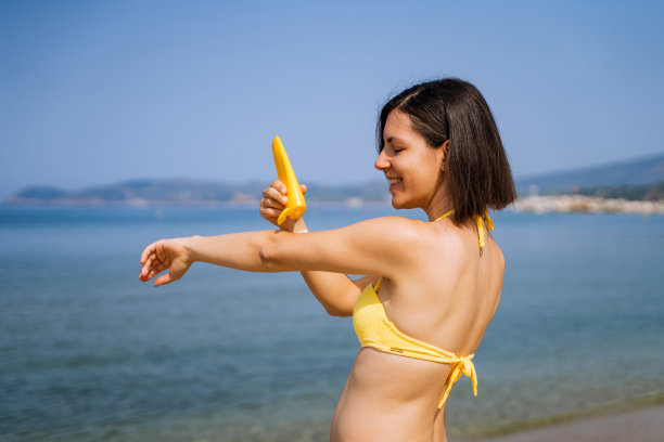 在海滩上涂防晒霜的女人图片下载