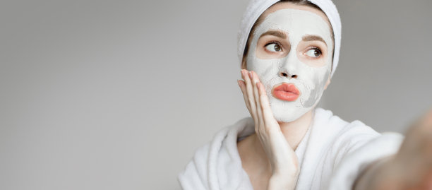 美丽快乐的女人的自拍肖像，她头上有毛巾送空气吻，脸上有粘土面具，隔离，早上的例行公事，呆在家里。横幅,复制空间图片下载
