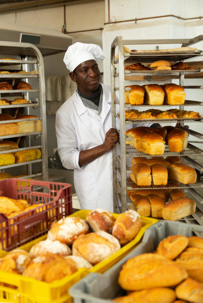 面包店老板把新鲜出炉的食物放在手推车上图片下载