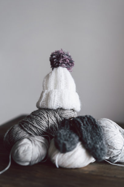 毛线球，针织小帽子和木制的针织针在木制的背景图片下载