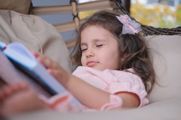 一个可爱的小女孩在秋千上看书图片下载