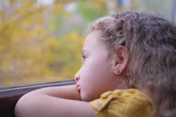 可爱的小女孩看着窗外。图片下载