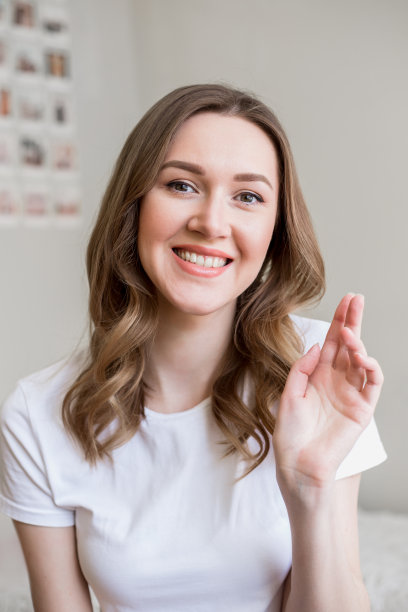 垂直肖像微笑的年轻女子坐在沙发上看镜头，女孩谈视频通话，女孩进行视频聊天对话图片下载