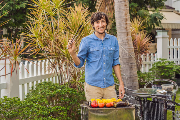 一个男人用火钳在后院烧烤图片下载