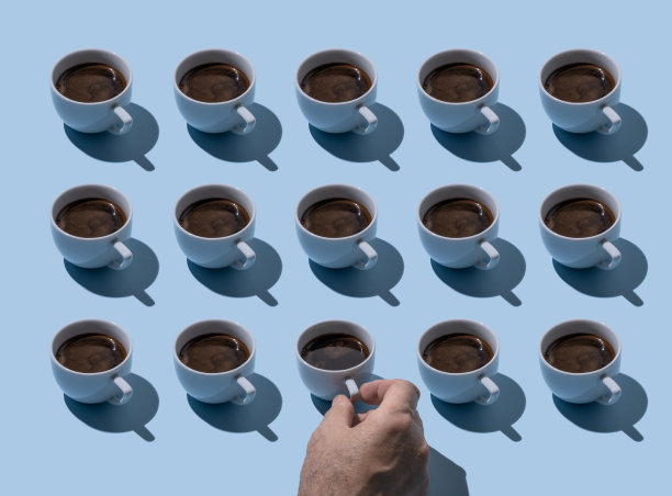 男性手拿着蓝灰色背景的一排咖啡杯图片下载