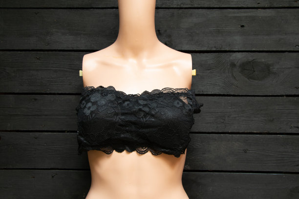 一个穿着黑色女性胸罩的塑料模特躺在一张木桌上，是个女性图片下载