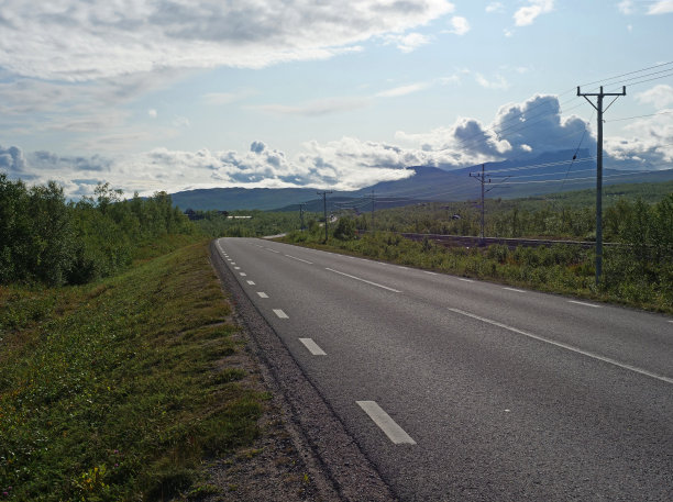 阿比斯科村和国家公园里孤独蜿蜒的柏油路和铁路，白桦林和山脉，夏天的蓝天白云图片下载
