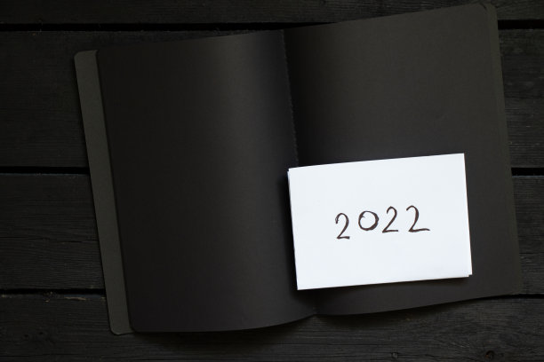 黑色白页笔记本，黑色木桌上写着2022，白页上写着2022，新年快乐图片下载