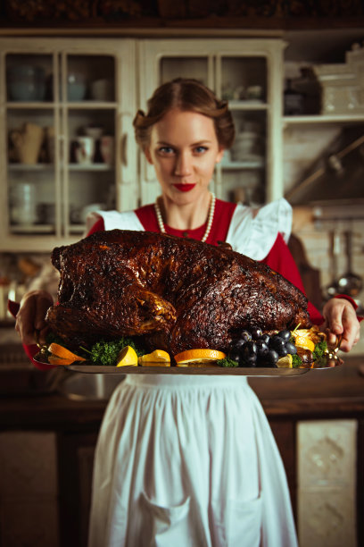 家庭主妇在厨房里拿着一只大火鸡，50年代的复古风格图片下载