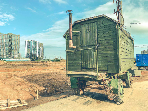 有轮子的木制马车。临时住所:建筑工人们在建筑工地上的临时住所带烟囱和小门的木屋图片下载