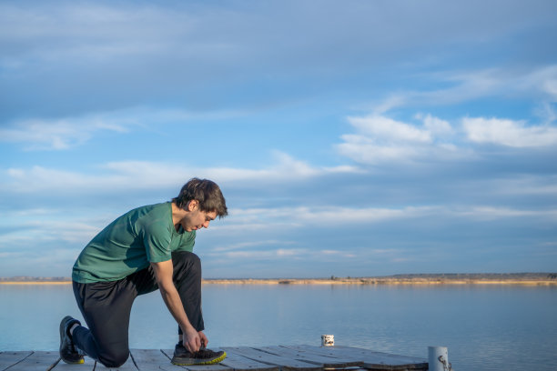 小男孩在蓝天下系鞋带图片下载