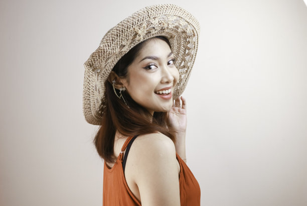 兴奋的亚洲女人戴着草帽在海滩度假，孤立在白色的工作室背景。图片下载