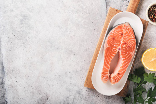 鲑鱼。生鲑鱼牛排。新鲜的生鲑鱼鱼与烹饪材料，香草和柠檬准备烤在浅灰色的背景。健康食品。前视图。副本的空间。图片下载