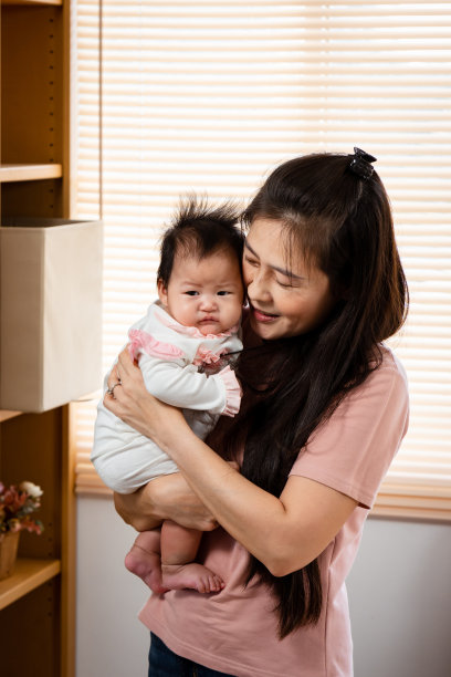 一位亚裔单身母亲在自己家的卧室里发现了抱着刚出生的女儿的姚。一个3个月大的新生儿刚从睡梦中醒来，被妈妈抱着。图片下载
