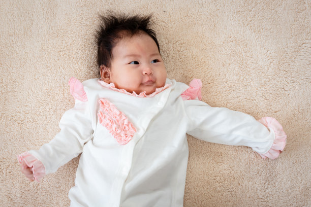 3个月大的亚洲新生女婴正开心地躺在床上，双手合十，放松，捂着脸，等待妈妈的照顾。图片下载