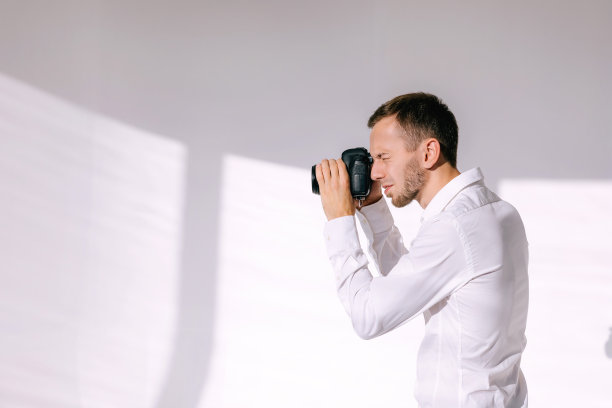 在白色摄影棚工作的摄影师的后台拍照图片下载