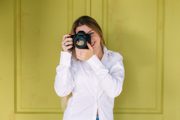 摄影师用相机遮住她的脸的肖像。图片下载