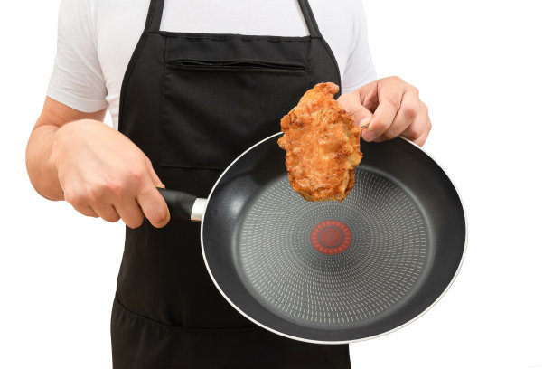 煎好的肉放在煎锅里，拿在厨师手里，孤立在白色的图片下载