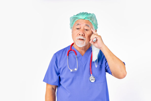 身穿制服的医生肖像，亚裔医生老人戴着白色背景的听诊器口罩。图片下载