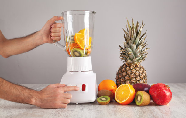 男子混合水果与电动搅拌器。图片下载