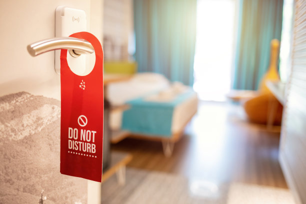 “请勿打扰”的牌子挂在门把手上。对物体进行特写，对部分文本进行选择性聚焦。酒店门上挂着请勿打扰的牌子。图片下载