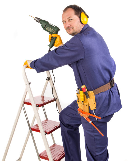 一个工人在楼梯上，手里拿着电钻。图片下载