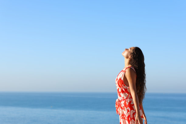 穿着红裙子的女人在海滩上呼吸着新鲜空气图片下载