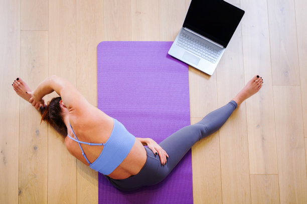 美丽的女孩在家里做瑜伽的俯视图，使用笔记本电脑图片下载