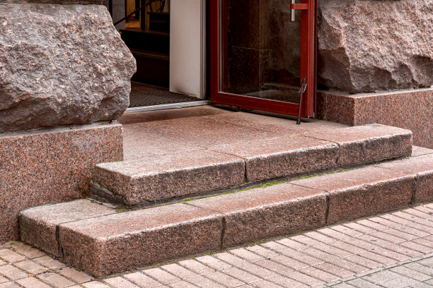 墙角的花岗岩台阶通往入口，敞开的大门上铺着棕色的框架和玻璃，门槛附近立面包覆着岩石，特写老城建筑的细节，无人知晓。图片下载