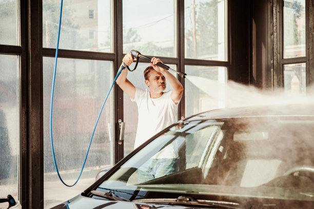 一名男子在自助洗车店用高压水管洗车图片下载