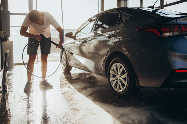 一名男子在自助洗车店用高压水管洗车图片下载