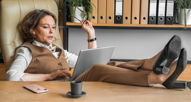 自信时尚成熟的中老年在职女性。工作中使用笔记本电脑，使用手机通话。总经理、首席执行官。年长的资深女商人，60多岁的西装女士，执行商业领袖。企业家的事业。会计在银行图片下载