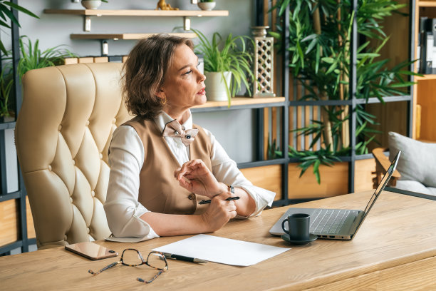 自信时尚成熟的中老年在职女性。工作中使用笔记本电脑，使用手机通话。总经理、首席执行官。年长的资深女商人，60多岁的西装女士，执行商业领袖。企业家的事业。会计在银行图片下载