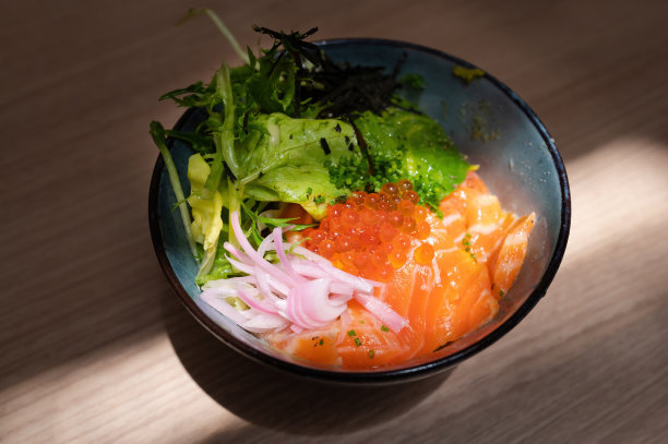 日本的一种米饭，上面放着新鲜的鲑鱼，鲑鱼子，洋葱片和蔬菜图片下载