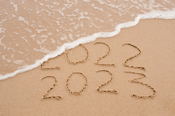 写在沙子上的数字2022和2023。2023年将取代2022年。海边的概念图片下载