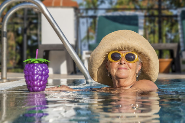 美丽的女人戴着帽子和墨镜在泳池边图片下载