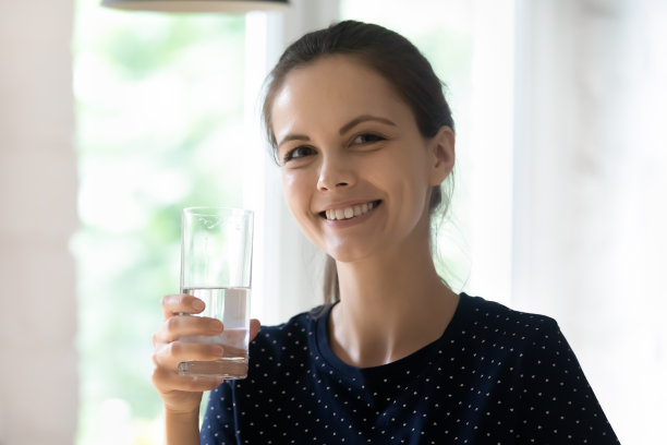 快乐开朗的美丽姑娘捧着清澈透明的水杯图片下载
