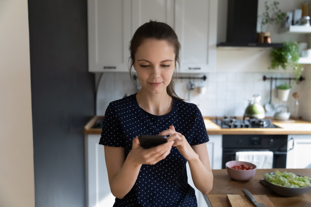 专注的年轻家庭主妇在厨房用手机图片下载