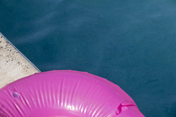 粉红色漂浮在游泳池的边缘图片下载