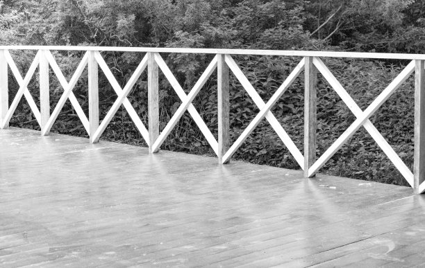 室外夏季露台与木制地板和栏杆的形式，在树木的背景下，特写，黑白镜头，单色图片下载