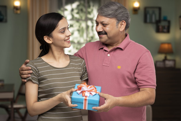 年幼的女儿在父亲节和他的生日给父亲一个礼盒，库存照片图片下载